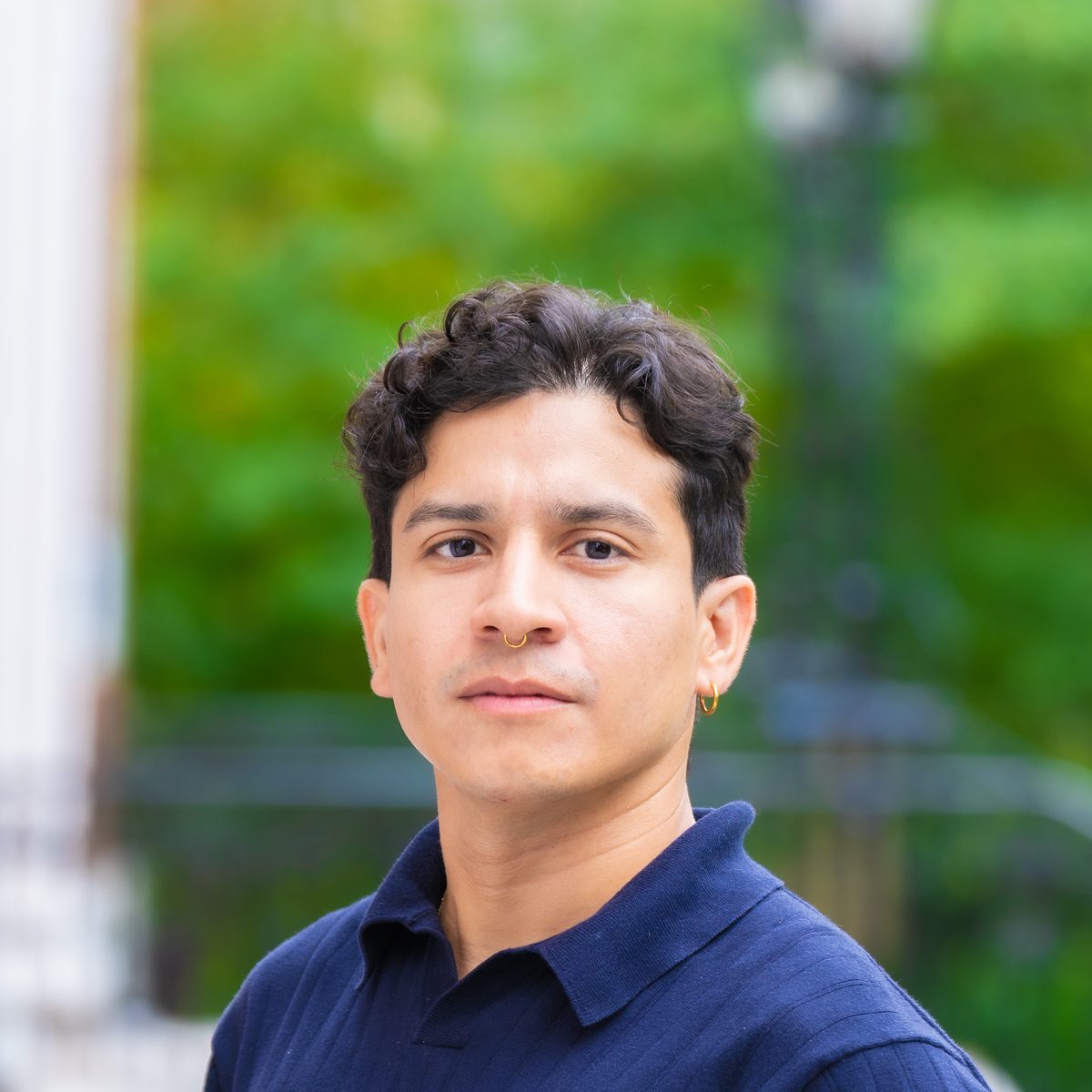 Rony Rodríguez-Ramírez outdoors on campus, in a navy polo shirt